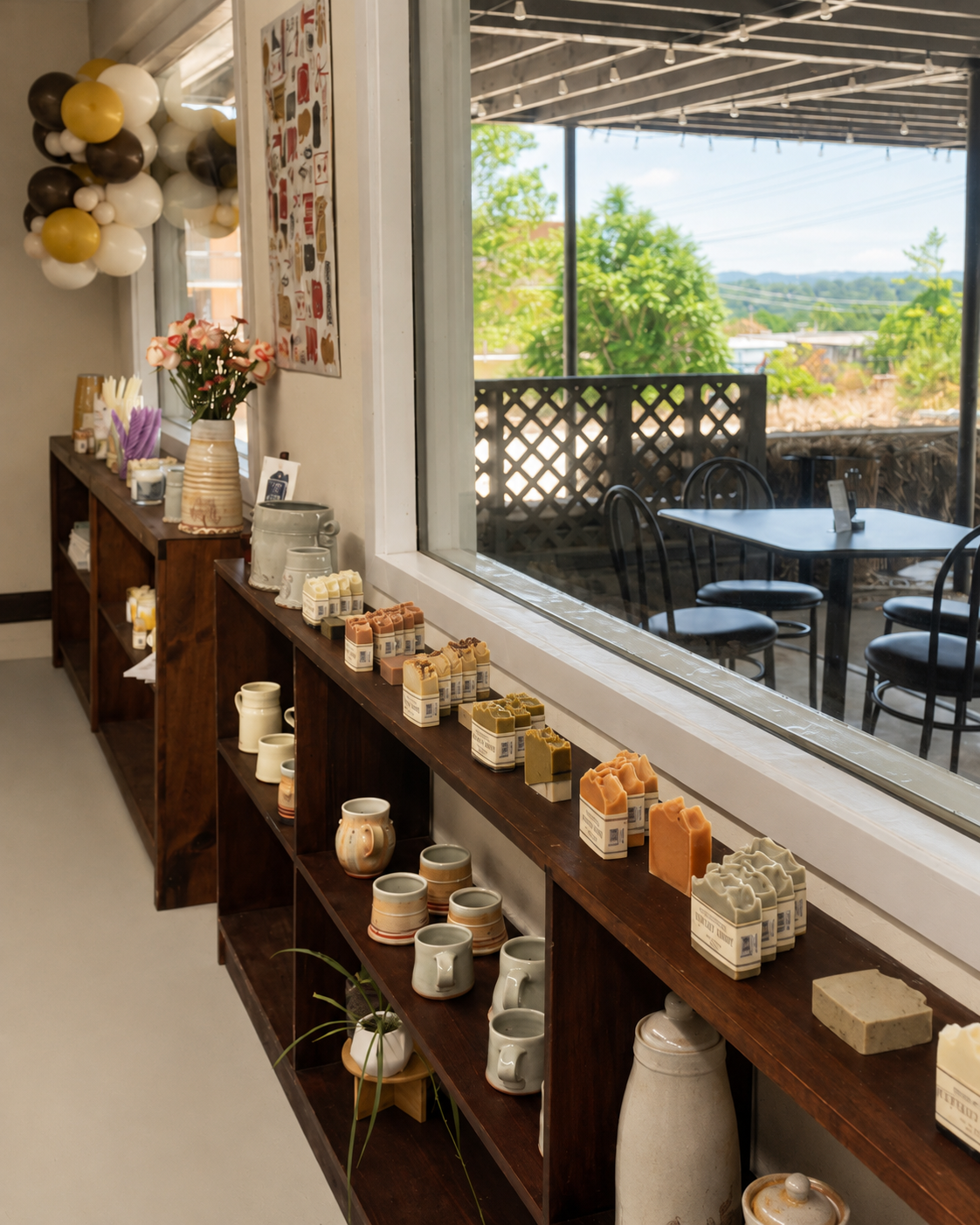 Shelves of handmade mugs and ceramics ready to paint beside a sunlit studio window